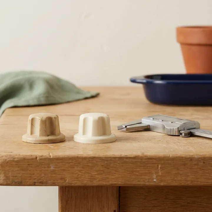 A cracked old appliance knob beside a new matching replacement knob and a pair of calipers